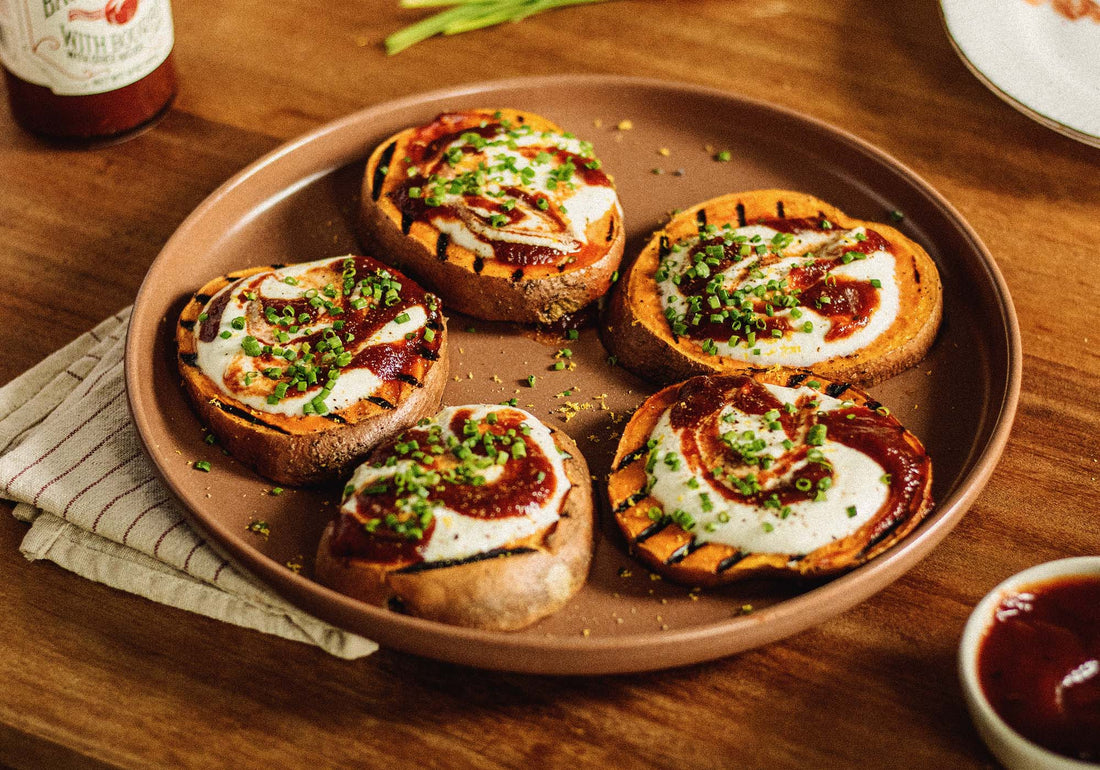 Serving plate with five medallion slices of grilled sweet potatoes topped with whipped feta, drizzled with Brownwood Farms Bacon Ketchup, and sprinkled with fresh chopped chives 
